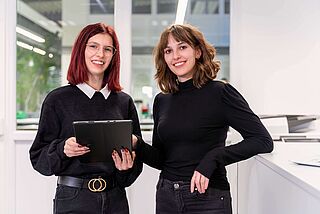 Zwei Mediengestalterinnen arbeiten am modernen Arbeitsplatz mit einem Tablet